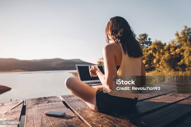 Young Woman Using Laptop Outdoor On Wooden Lake Pier Stock Photo - Download Image Now