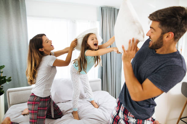 familia teniendo pelea de almohadas en el dormitorio - bed couple pillow fight men fotografías e imágenes de stock