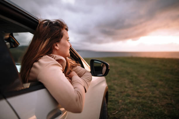 istock Young woman watching a beautiful sunset from her car 1271110933