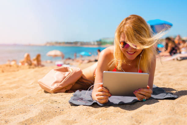istock Woman watching movie on tablet computeron the beach 1271112033