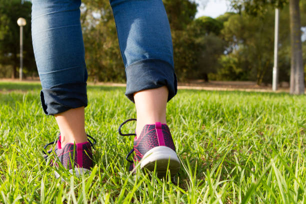 istock Woman with sneakers and jeans walking on grass 1271112058