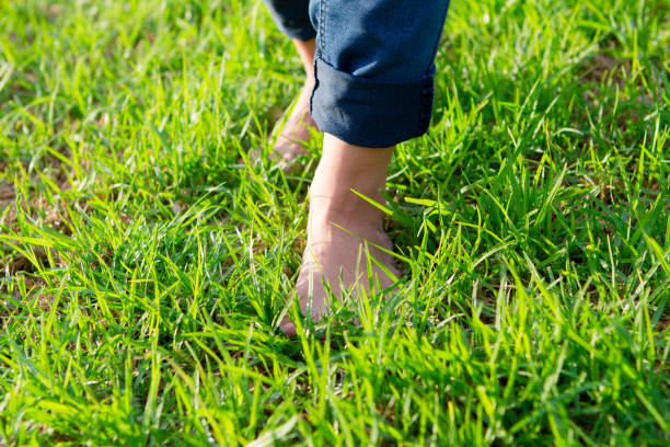 istock Woman with barefoots and jeans walking on grass. 1271112060