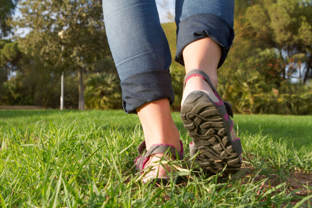 istock Woman with flips and flop and jeans walking on grass. 1271112103