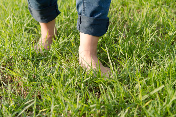 istock Woman with barefoots and jeans walking on grass. 1271112122