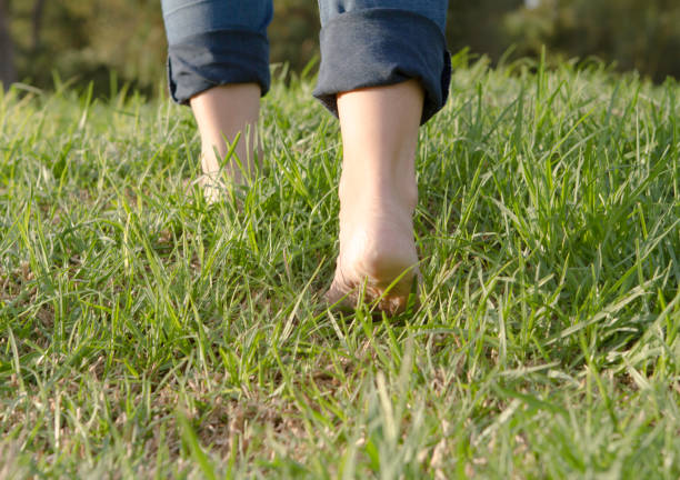 istock Woman with barefoots and jeans walking on grass. 1271112130