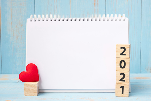 blank notebook and 2021 cubes with red heart shape decoration on blue wooden table background. New Year NewYou, Goal, Resolution, health, Love and Happy Valentine
