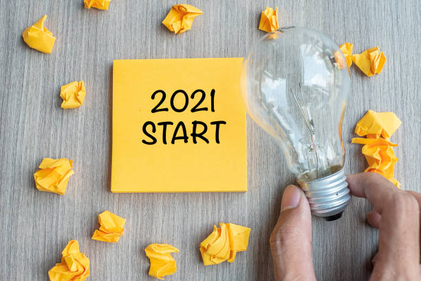 istock 2021 Start words on yellow note and crumbled paper with Businessman holding lightbulb on wooden table background. New Year New Idea Creative, Innovation, Imagination, Resolution and Goal concept 1271112345