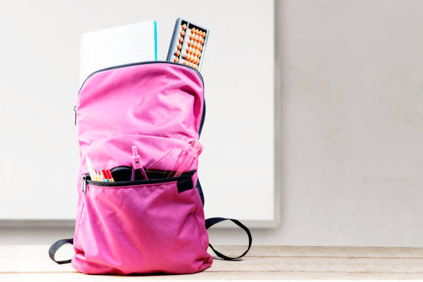 istock Backpack with book and stationary on wooden table with a whiteboard background 1271112582
