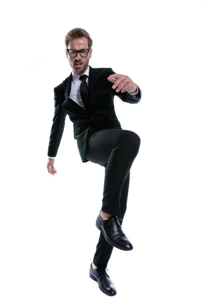 istock cool unshaved man in black suit holding knee up 1271112654