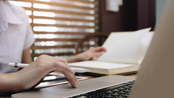 istock Young  woman sitting at table and taking notes in notebook.On table is laptop. 1271115247