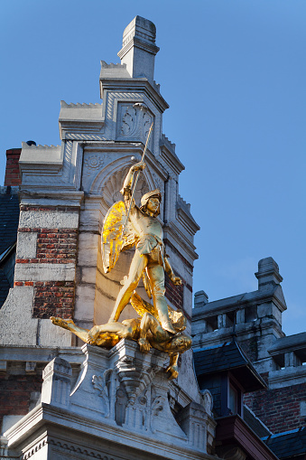 Golden archangel Michael slaying devil in Brussels at facade of medieval building in street Rue Andre. Historical arts. Archangel is patron of Brussels