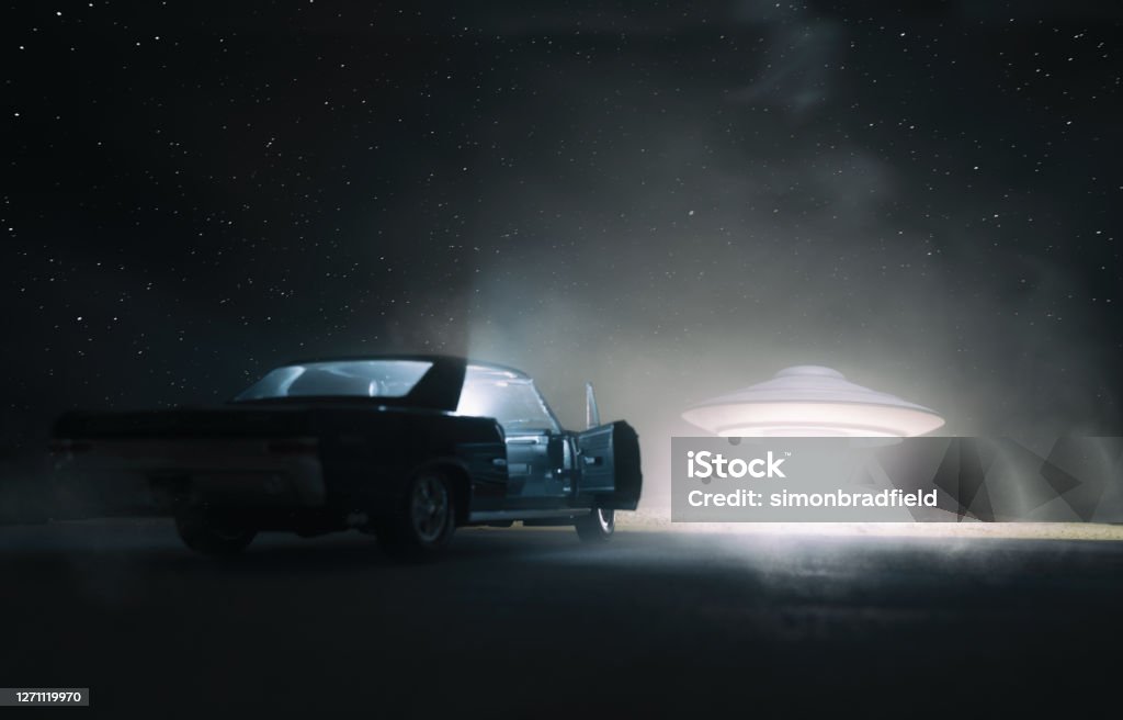 UFO Encounter A UFO hovers over a desert, and an old car is parked in the foreground. Is someone getting abducted, or is someone hitching a ride? UFO Stock Photo