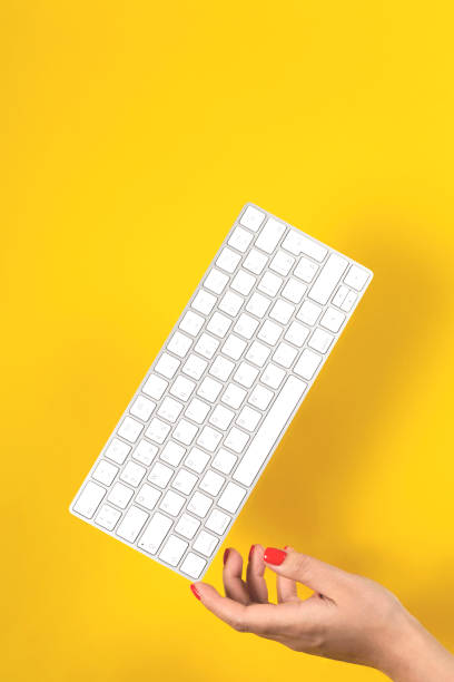 wagi klawiatury na kobiecej dłoni na żółtym tle - machine typewriter human hand typing zdjęcia i obrazy z banku zdjęć