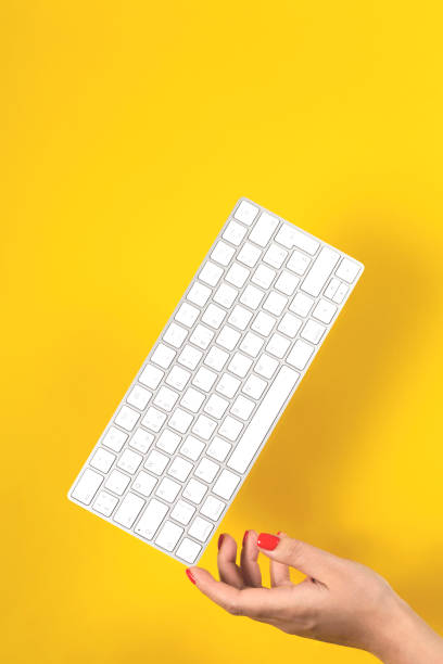 keyboard balances on woman's hand on yellow background - author writing retro revival women imagens e fotografias de stock