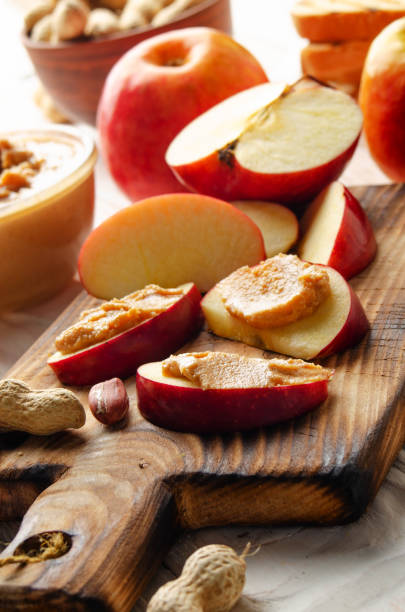istock Cut board with apple slices with peanut butter on white wooden kitchen table 1271122930