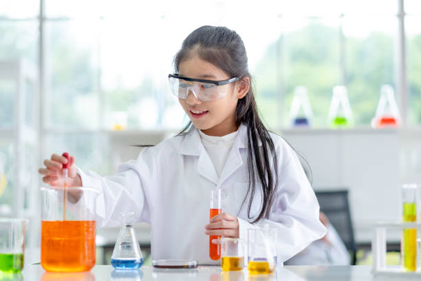 lovely little girl enjoy and excite to examine the color chemical in laboratory by using dropper with day light - smiling research science and technology clothing imagens e fotografias de stock