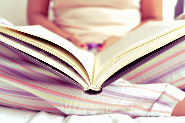 istock young woman reading a book in bed 1271129288