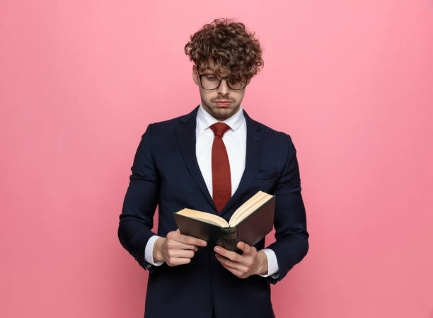 zszokowany młody biznesmen w książce do czytania garnituru - book holding necktie businessman zdjęcia i obrazy z banku zdjęć