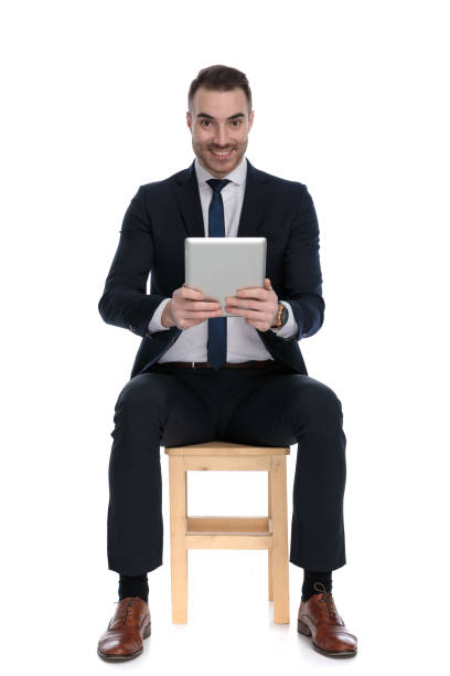 istock Happy businessman smiling and holding tablet while sitting 1271129957