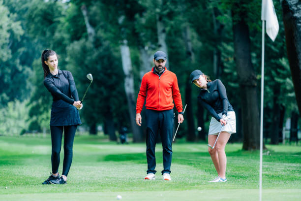 istock Two young golfers practicing chipping shots on a golf course with golf instructor 1271133966