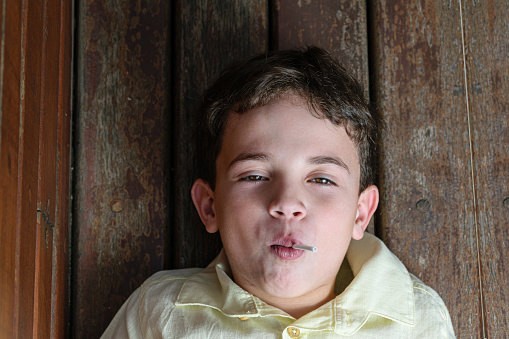 7 year old Brazilian child in a photo session at the nursery on a sunny afternoon. Eating lollipop and white chocolate.