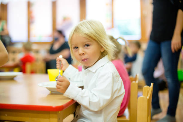 Toddler child, eating breakfast in kindergarten