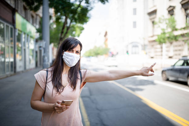 istock Woman with a protective facial mask using mobile phone 1271139011