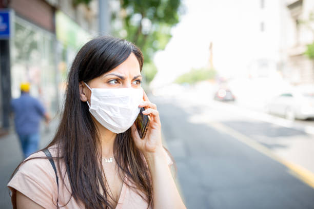 istock Woman with a protective facial mask using mobile phone 1271139061