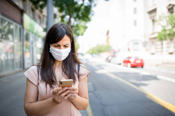 istock Woman with a protective facial mask using mobile phone 1271139108
