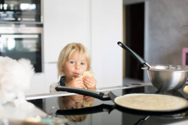 istock Cute toddler child, blond boy, making pancake in kitchen 1271140435
