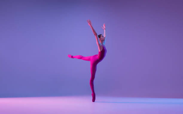 istock Young and graceful ballet dancer isolated on purple studio background in neon light 1271142069
