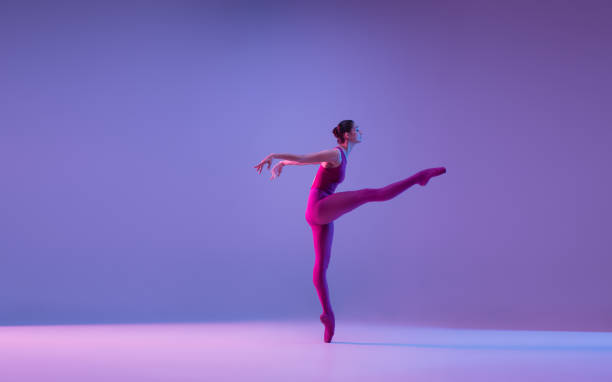 istock Young and graceful ballet dancer isolated on purple studio background in neon light 1271142076