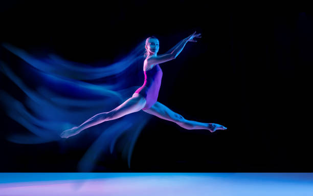istock Young and graceful ballet dancer isolated on black studio background in neon mixed light 1271142077