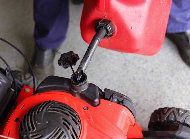 A close up image of an African-American man adding gasoline in a lawnmower stock photo