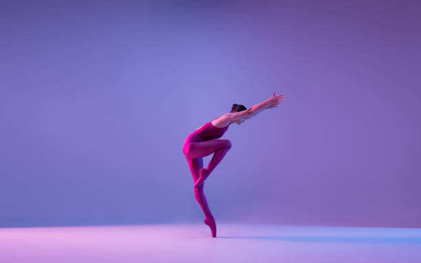 istock Young and graceful ballet dancer isolated on purple studio background in neon light 1271142079