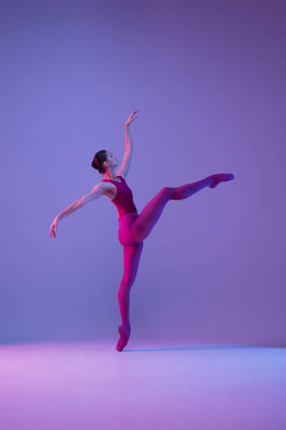 istock Young and graceful ballet dancer isolated on purple studio background in neon light 1271142109