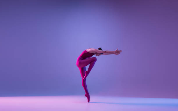 istock Young and graceful ballet dancer isolated on purple studio background in neon light 1271142114