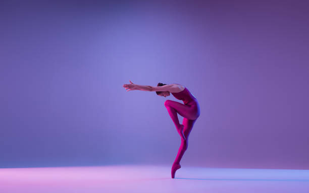 istock Young and graceful ballet dancer isolated on purple studio background in neon light 1271142115