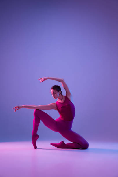 istock Young and graceful ballet dancer isolated on purple studio background in neon light 1271142134