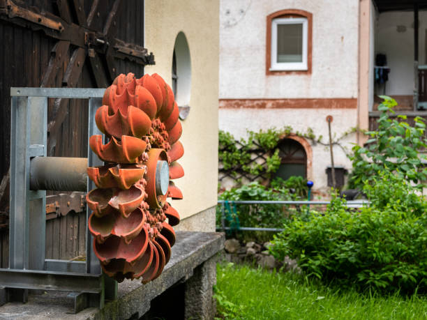 An old orange Pelton wheel hanging outside, cloudy day in the Austrian Alps