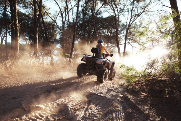 donna bionda che indossa casco in quad in salita nella foresta - off road vehicle quadbike 4x4 adventure foto e immagini stock