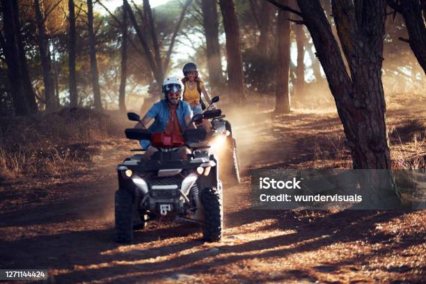 Two Friends Wearing Helmets Having Fun And Riding Quad Bikes Together In The Forest Stock Photo - Download Image Now