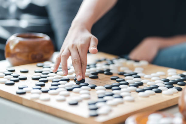 istock hand putting baduk blackstone on wooden grid board 1271144449