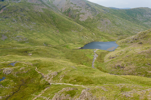 Aerial view of a small lake in a rugged mountain pass (Styhead Pass, Lake District, England)