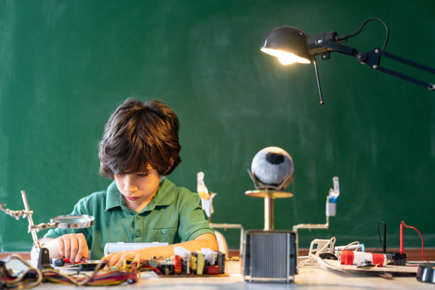 istock Elementary Schoolboy Working On Robotics And Coding In Front Of Green Chalkboard 1271147047