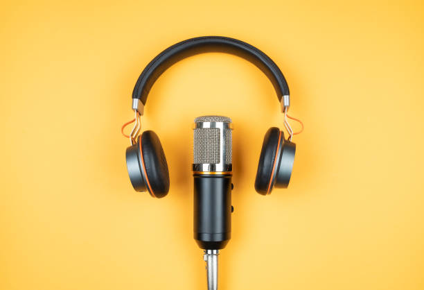 directly above view of headphones and recording microphone on orange background stock photo