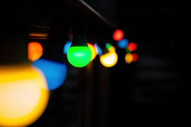 Coloured bulbs bokeh background with space for text. Festive string of lights in green, yellow, blue and red, suitable for holiday or Christmas themed images.