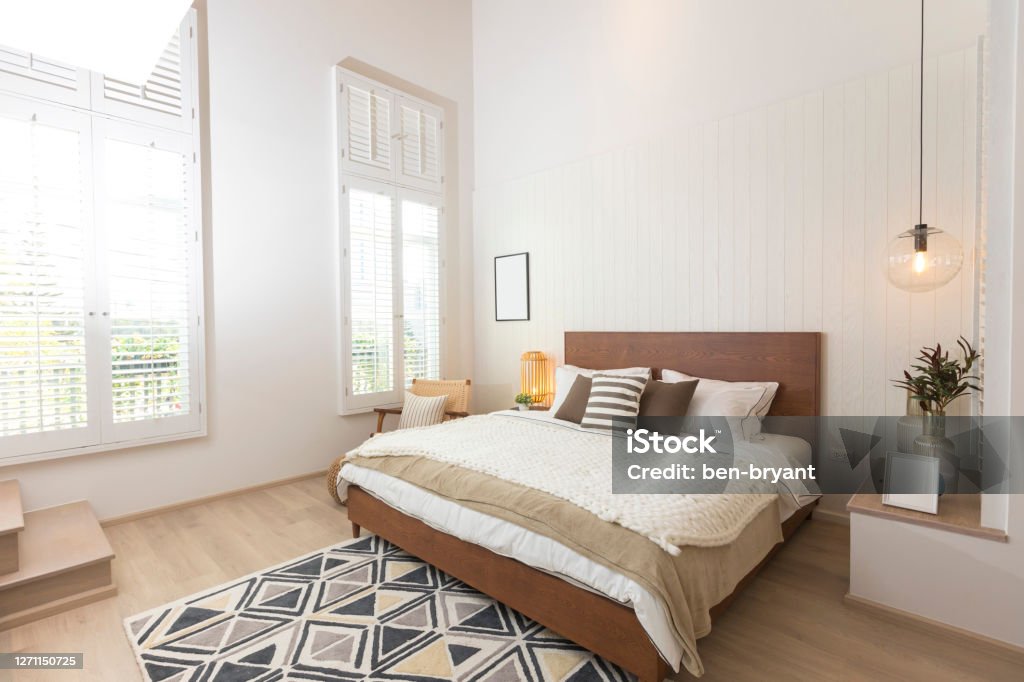 Master bedroom in rustic style and hanging lamp. Master bedroom in rustic style with minimalist white double bed and hanging lamp. Owner's Bedroom Stock Photo