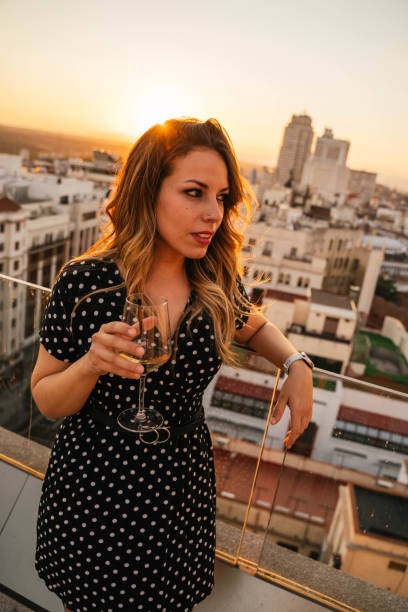 istock Young woman drinking wine on a rooftop during sunset in Madrid 1271151431