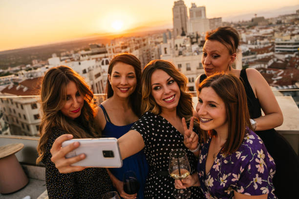 Group of friends taking a selfie on a rooftop in Madrid during sunset Group of friends taking a selfie on a rooftop in Madrid with a festive atmosphere while they drink and watch the sunset selfie madrid photos stock pictures, royalty-free photos & images